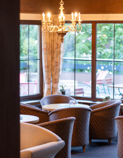 Lounge Cresta Garni mit Tischen, Stühlen und Lampen sowie Aussicht auf die Terrasse