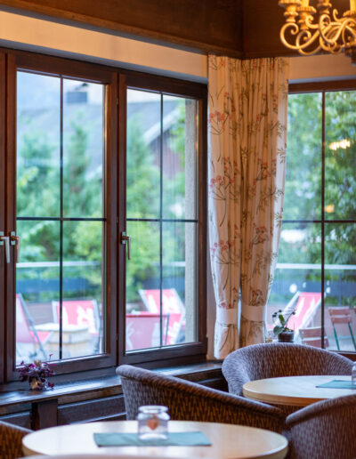 Lounge Cresta Garni mit Tischen, Stühlen und Lampen sowie Aussicht auf die Terrasse