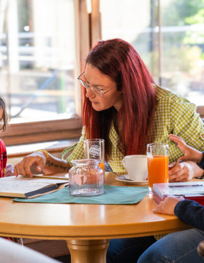 Mutter und Kinder haben Spaß in der Lounge mit Buch, Spiel, Säften und Kaffee sowie Ausblick auf die Terrasse