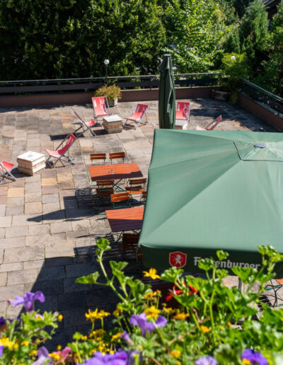 Blick auf Terrasse von oben mit Stühlen, Tischen und großen Sonnenschirmen